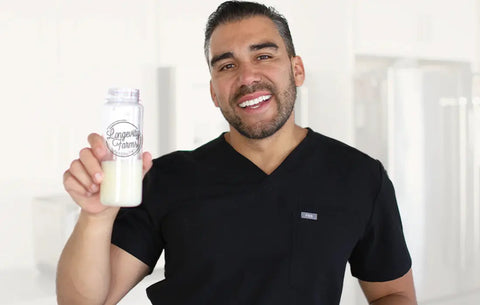 NAD+ supplement for aging held by smiling man in black shirt with Longevity Farms shaker bottle.