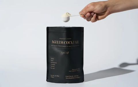 Anti-aging health drinks powder being scooped from a Longevity Farms Ageless Cocktail pouch