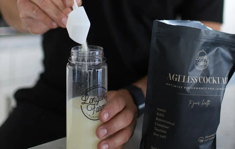 NAD precursor powder being added to Longevity Farms bottle beside Ageless Cocktail supplement bag.