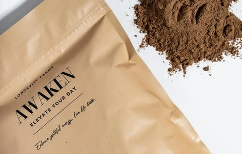Longevity drink powder spilled beside Awaken supplement bag with ingredients promoting energy and mood