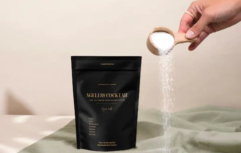 NAD+ supplementation shown as Ageless Cocktail powder being poured from a wooden scoop next to product bag.