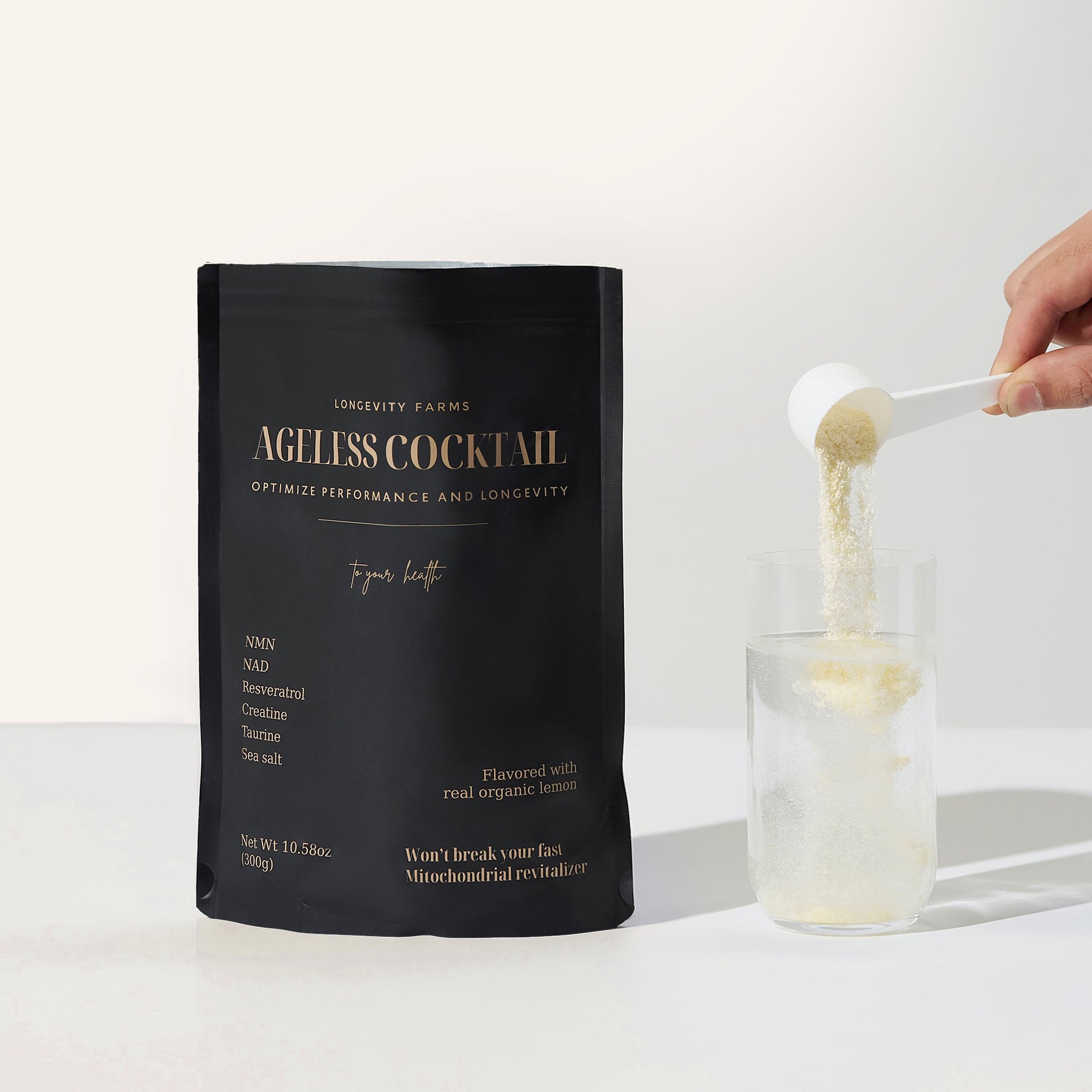 NMN supplement powder called Ageless Cocktail being poured into a glass of water, with black longevity-focused packaging.